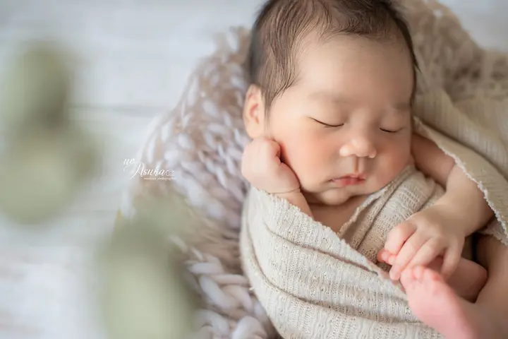 ニューボーンフォト_ニュートラルカラーの布に包まれて眠る赤ちゃん