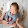 ニューボーンフォト灰色の布に包まれたバスケットの赤ちゃん
