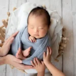 ニューボーンフォト灰色の布に包まれたバスケットの赤ちゃん