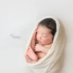 ニューボーンフォト_白い布で包まれた穏やかな新生児