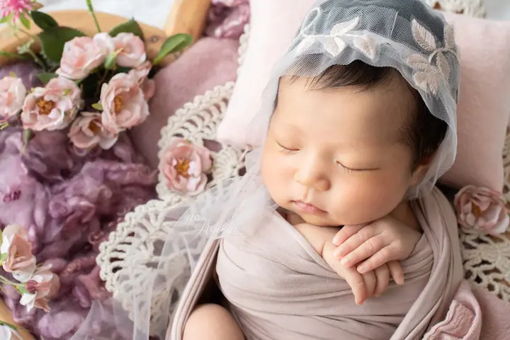 ニューボーンフォト_お花とレースのベールに包まれたピンクのおくるみの新生児