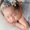 ニューボーンフォト_フラワーヘッドバンドとグレーのおくるみに包まれた新生児