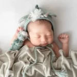 ニューボーンフォト_グリーンのニット帽とぬいぐるみを抱く新生児