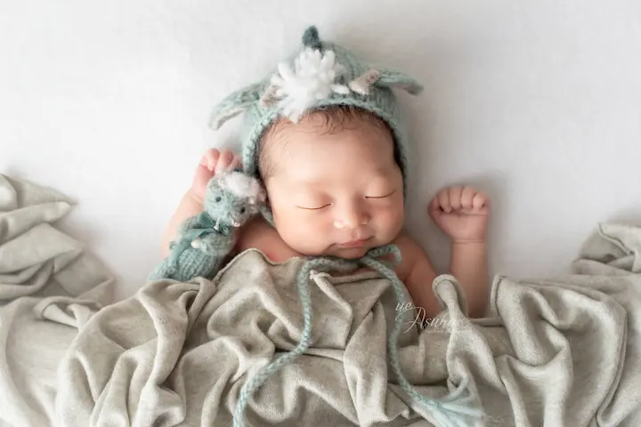 ニューボーンフォト_グリーンのニット帽とぬいぐるみを抱く新生児
