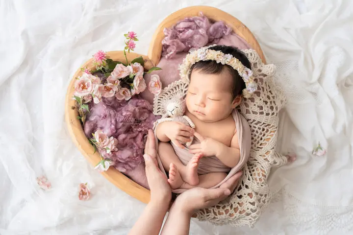 ニューボーンフォト_花冠をつけてママの手に包まれるハートバスケットの新生児