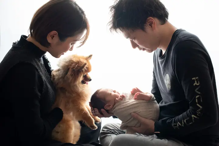 ニューボーンフォト_犬と両親に見守られる逆光のニューボーンフォト
