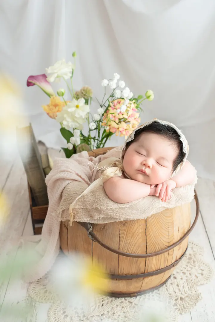 ニューボンフォト_生花を添えた木製バケツで眠る新生児