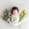 ニューボンフォト_花のハンモックでウサギを抱く新生児