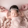 ニューボーンフォト_ピンクの布に包まれ、両親と手をつなぐ新生児