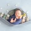 ニューボンフォト_ぬいぐるみと星モチーフハンモックに包まれる新生児