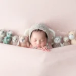 ニューボーンフォト_ピンクの背景でぬいぐるみに囲まれた新生児
