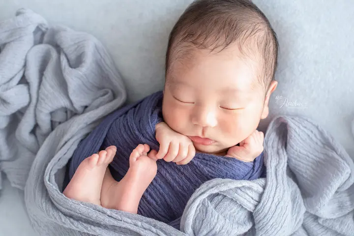 ニューボーンフォト_グレーのラップに包まれた穏やかな新生児