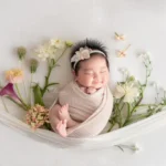 ニューボーンフォト_新生児微笑：花のハンモックで微笑む赤ちゃん