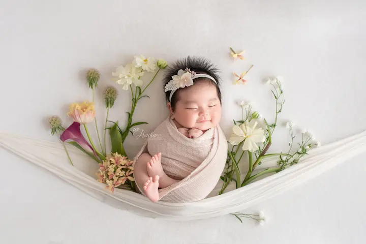 ニューボーンフォト_新生児微笑：花のハンモックで微笑む赤ちゃん